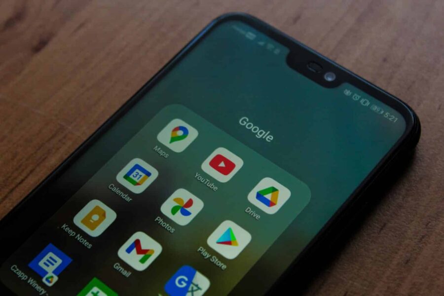 Close-up of a smartphone showing various Google apps on its screen.