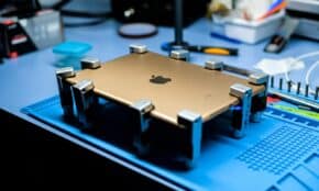 A close-up view of a tablet undergoing repair in a tech workshop with specialized tools.