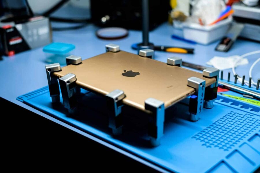 A close-up view of a tablet undergoing repair in a tech workshop with specialized tools.