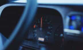 Focused image of a car's speedometer and tachometer under dim lighting, showing mileage and speed.