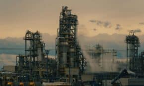 A detailed view of a refinery's towers against a cloudy dusk sky, showcasing industrial architecture.