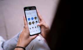 Close-up of a woman using a smartphone with social media app open. Hands holding device.