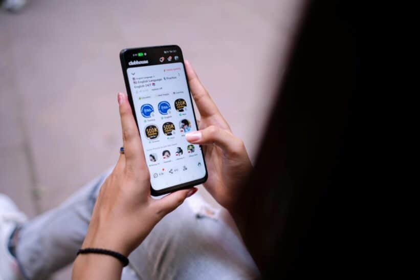 Close-up of a woman using a smartphone with social media app open. Hands holding device.