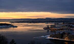 Aerial sunset view of Oslo Fjord with city skyline and dramatic clouds.