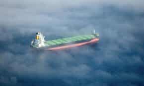 Aerial shot of a container ship sailing through fog near Cape Town, South Africa.