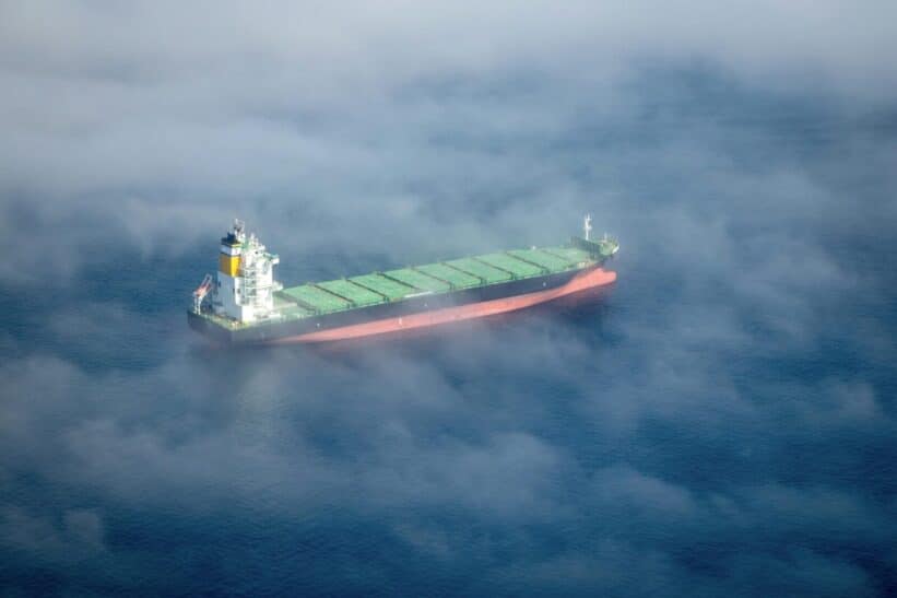 Aerial shot of a container ship sailing through fog near Cape Town, South Africa.