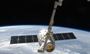 View of a spacecraft docked at the ISS above Earth with visible solar panels.