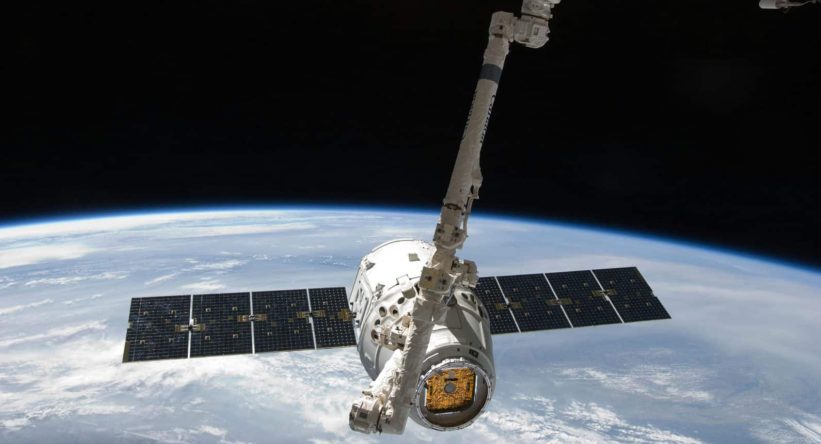 View of a spacecraft docked at the ISS above Earth with visible solar panels.