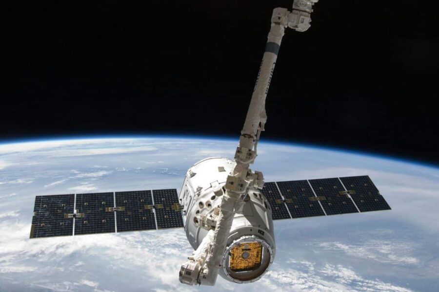 View of a spacecraft docked at the ISS above Earth with visible solar panels.