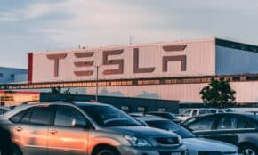 Tesla factory with parked cars during sunset, showcasing modern automotive industry vibes.