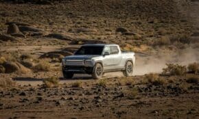 Electric pickup truck navigating a rocky desert landscape, showcasing off-road capability and rugged terrain.