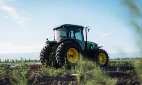 A vibrant green tractor on a farm in Mendoza, Argentina, under clear blue skies.