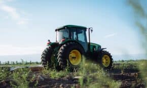 A vibrant green tractor on a farm in Mendoza, Argentina, under clear blue skies.