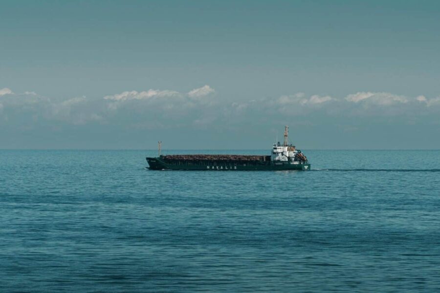 A cargo ship cruising through calm ocean waters under a clear sky.