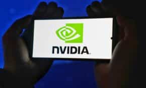 Hands holding a smartphone showing the NVIDIA logo on a bright screen.