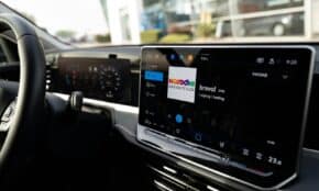 Inside view of a car with a sleek digital dashboard showing navigation and media controls.