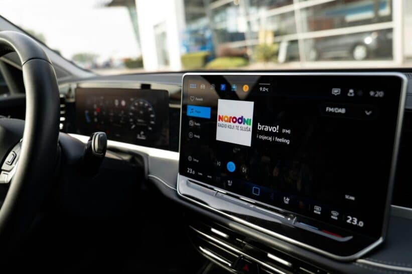 Inside view of a car with a sleek digital dashboard showing navigation and media controls.