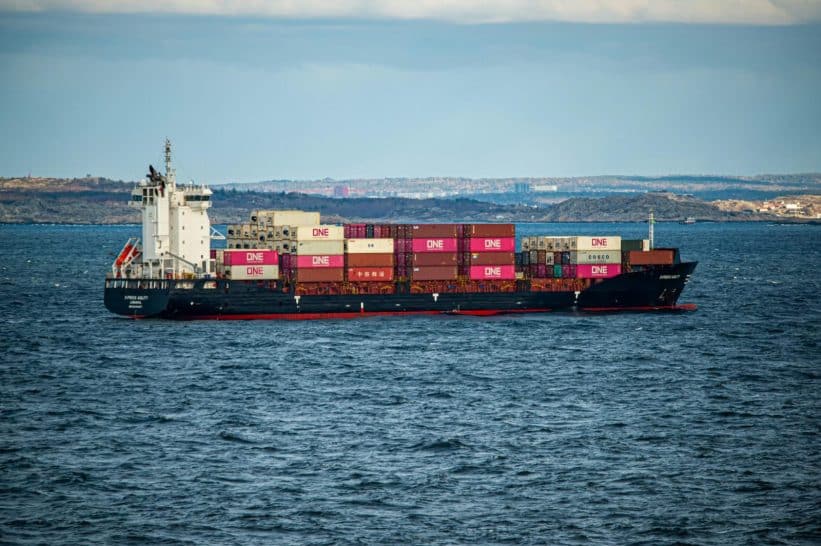 A large container ship transports cargo across the open sea under a clear sky. Ideal for shipping and logistics themes.