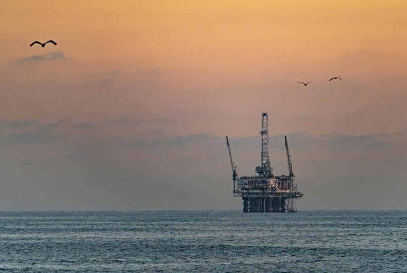 Oil platform silhouetted against a vibrant sunset in Huntington Beach, California.