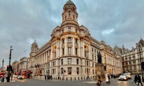 A bustling street scene featuring a grand Edwardian building in Central London at dusk, showcasing urban life.