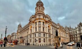 A bustling street scene featuring a grand Edwardian building in Central London at dusk, showcasing urban life.