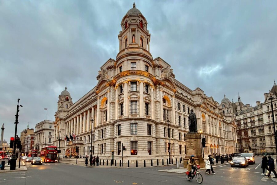 A bustling street scene featuring a grand Edwardian building in Central London at dusk, showcasing urban life.