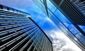 Low angle view of modern skyscrapers with reflective glass against a bright blue sky.