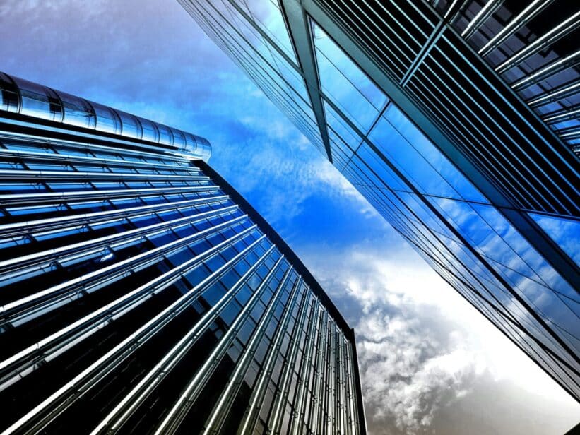 Low angle view of modern skyscrapers with reflective glass against a bright blue sky.