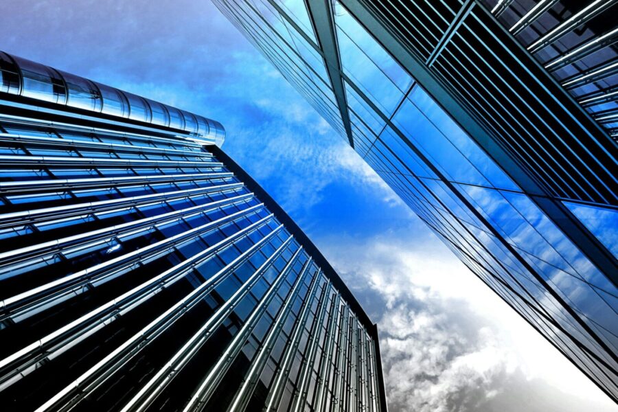 Low angle view of modern skyscrapers with reflective glass against a bright blue sky.