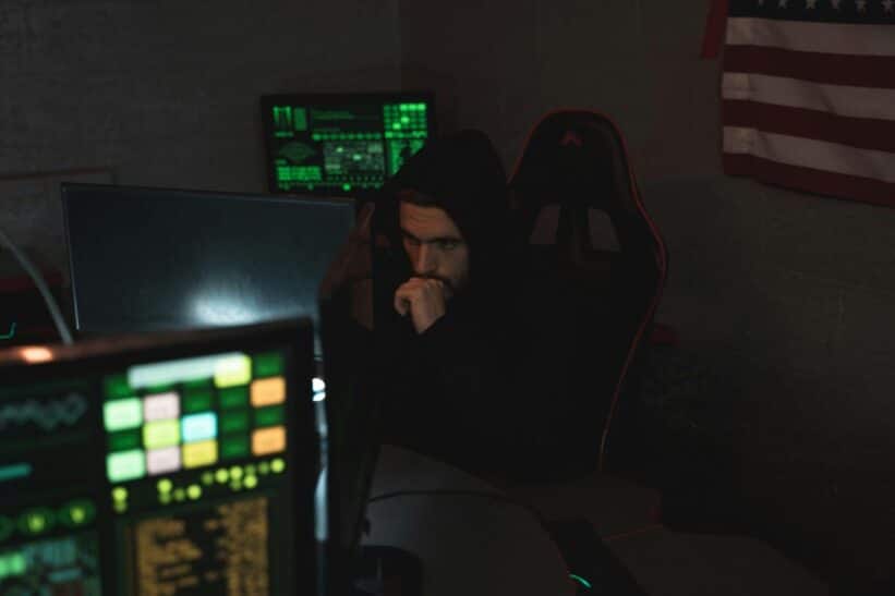 A cybersecurity expert monitors multiple screens, focused on data protection in a dark room.
