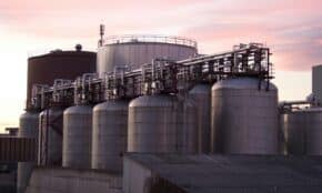 A refinery with large stainless steel storage tanks during sunset, showcasing industrial infrastructure.