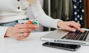 Close-up of a woman using a credit card for online shopping on a laptop, emphasizing digital transactions.