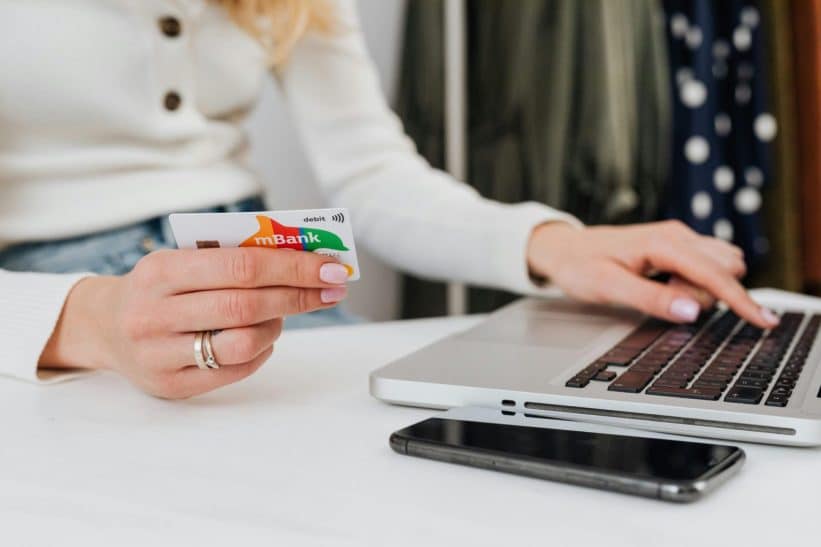 Close-up of a woman using a credit card for online shopping on a laptop, emphasizing digital transactions.