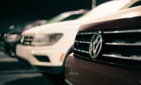 Front bumpers of expensive prestige automobiles at market retailing new cars at night