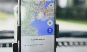 A smartphone displaying GPS map of New York City secured in a car mount during daylight.