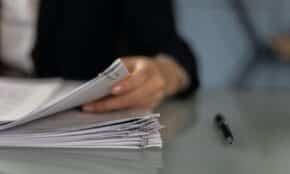 Close-up of a professional organizing a stack of documents on a desk.