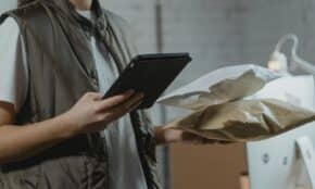 A person using a tablet to manage packages in an indoor setting, highlighting technology and logistics.