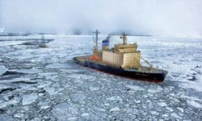 Icebreaker ship cutting through vast frozen ocean, showcasing winter exploration.