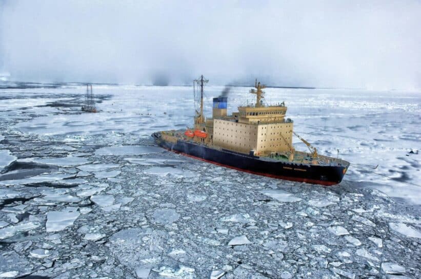 Icebreaker ship cutting through vast frozen ocean, showcasing winter exploration.