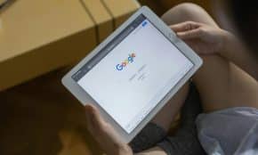 Close-up of hands holding a tablet showing the Google search page.