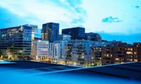 Illuminated modern buildings in Oslo's downtown at twilight, showcasing architecture.