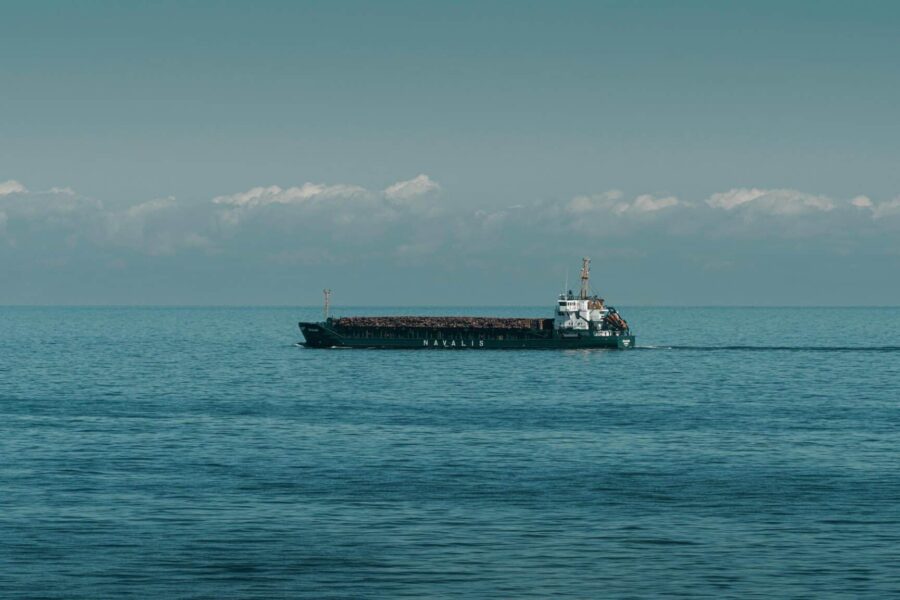 A cargo ship cruising through calm ocean waters under a clear sky.