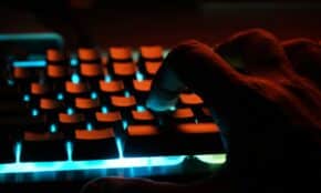 persons hand on blue lighted computer keyboard