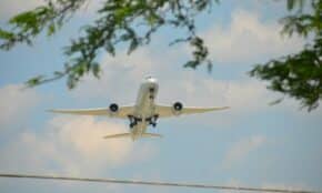 An airplane is flying in the sky above a power line