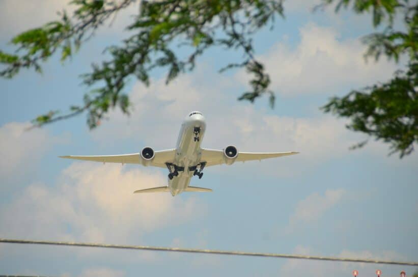 An airplane is flying in the sky above a power line