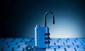An unlocked padlock rests on a computer keyboard.