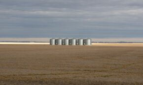 Silos stand in a vast, empty field.