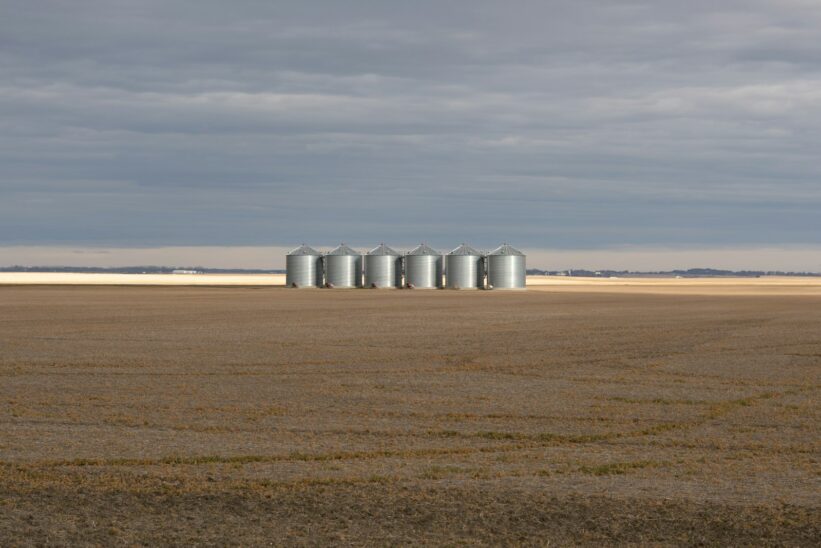 Silos stand in a vast, empty field.