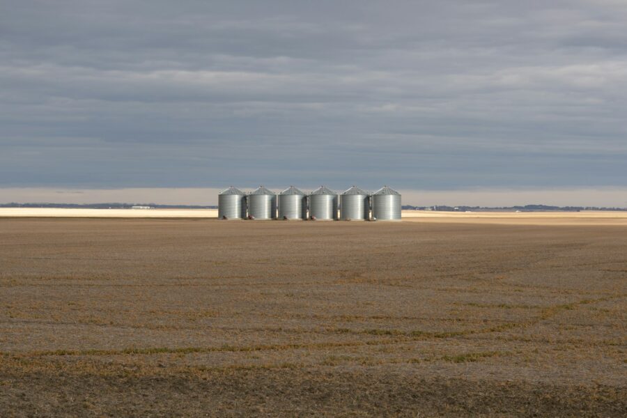 Silos stand in a vast, empty field.