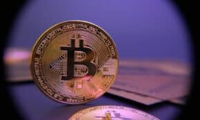 Bitcoin coin displayed on a purple background.